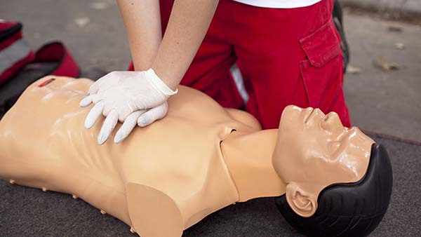 Individual performing CPR on a training dummy at a safety training and consulting company